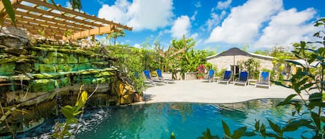 Una piscina al aire libre, sombrillas, sillones reclinables de piscina