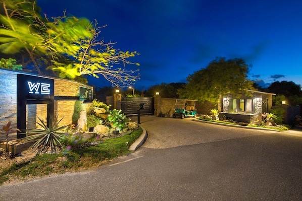 A well-lit entrance with a sign reading "WE" and a stone wall with plants. - Kokomo Botanical Resort - Caribbean Family Cottages (Providenciales)