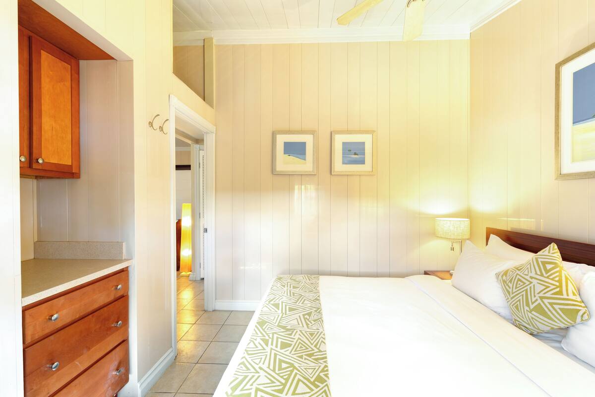 Ein Hotelzimmer mit einem Bett, einem Holzschrank und zwei gerahmten Bildern an der Wand.