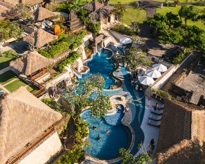 An aerial view of a resort with multiple swimming pools, a central water feature, and surrounding lush greenery. - RIMBA by AYANA Bali (Jimbaran)