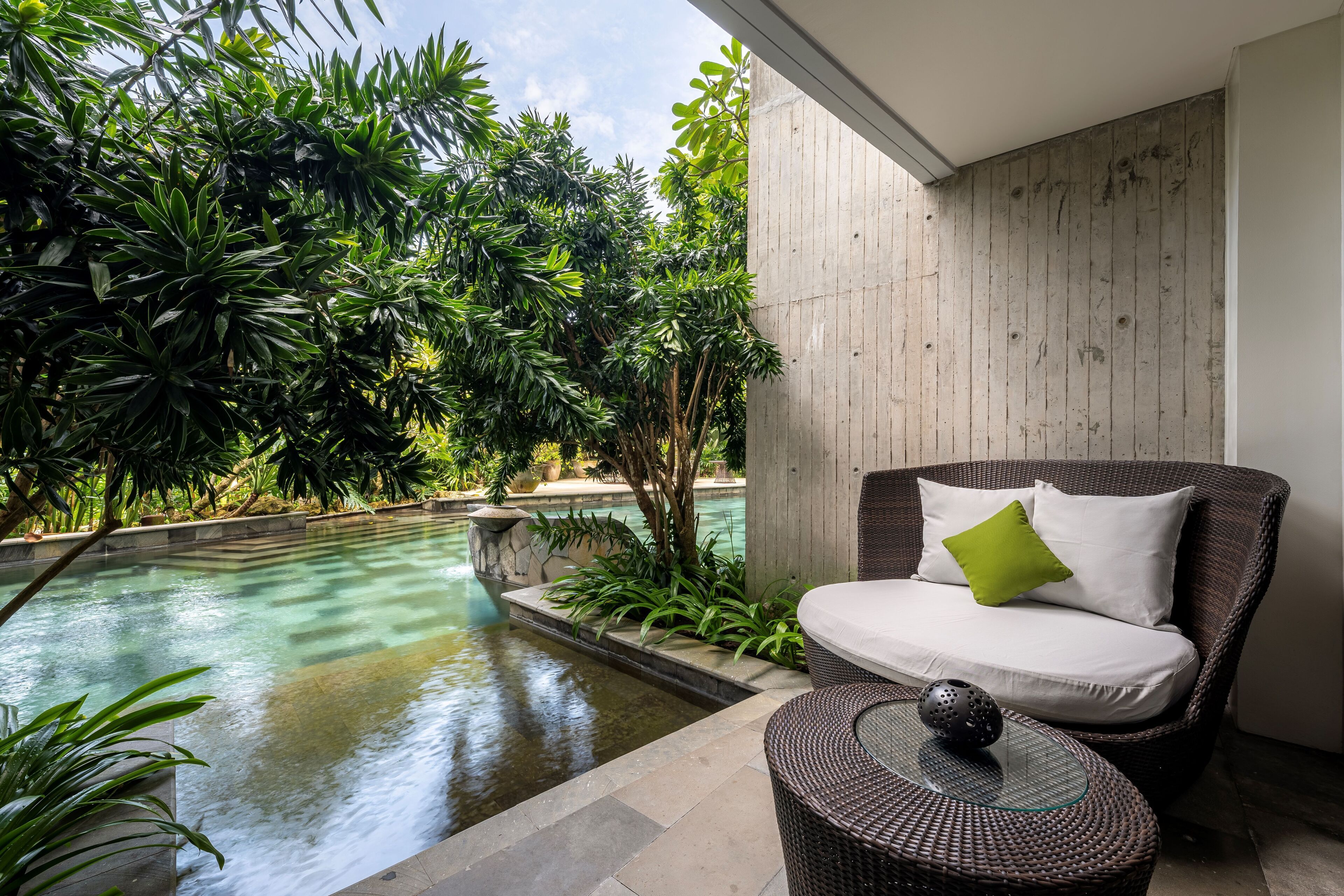 Un área de estar moderna al aire libre con piscina, rodeada de exuberante vegetación.