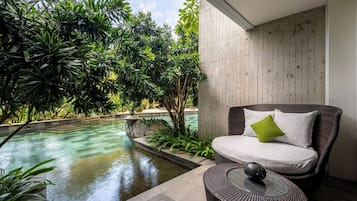 Un área de estar moderna al aire libre con piscina, rodeada de exuberante vegetación.