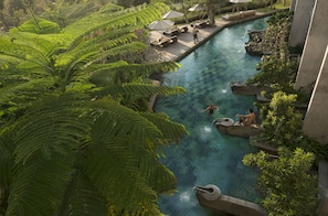 An indoor swimming pool with lush greenery and lounge areas.