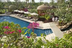 A pool area with lounge chairs, umbrellas, and a gazebo. - RIMBA by AYANA Bali (Jimbaran)