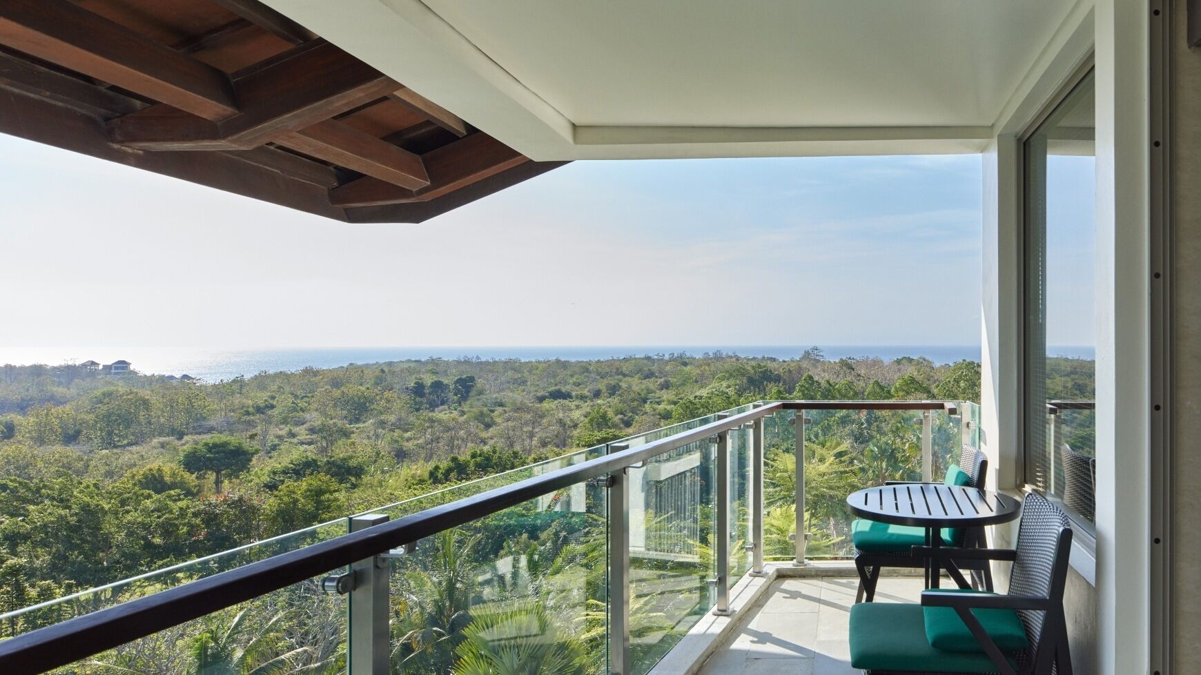 A balcony with a glass railing overlooking a lush landscape.