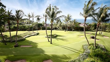 Golfers can enjoy a serene round amidst lush tropical trees and ocean views.