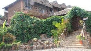 A building with a thatched roof, stone walls, and a balcony with a metal railing. - Osoita Lodge (Ongata Rongai)