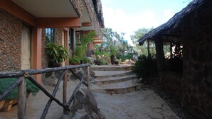 A stone pathway leading to a building with a thatched roof structure. - Osoita Lodge (Ongata Rongai)
