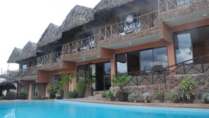 A hotel with multiple rooms, a swimming pool, and a balcony with a thatched roof. - Osoita Lodge (Ongata Rongai)