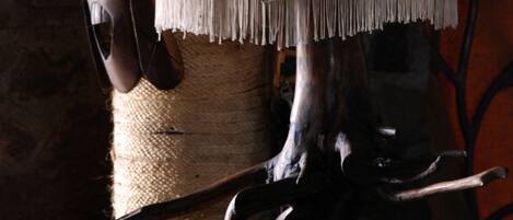 A rustic interior with a wooden sculpture, a pair of boots, and a lamp with a fringed shade.
