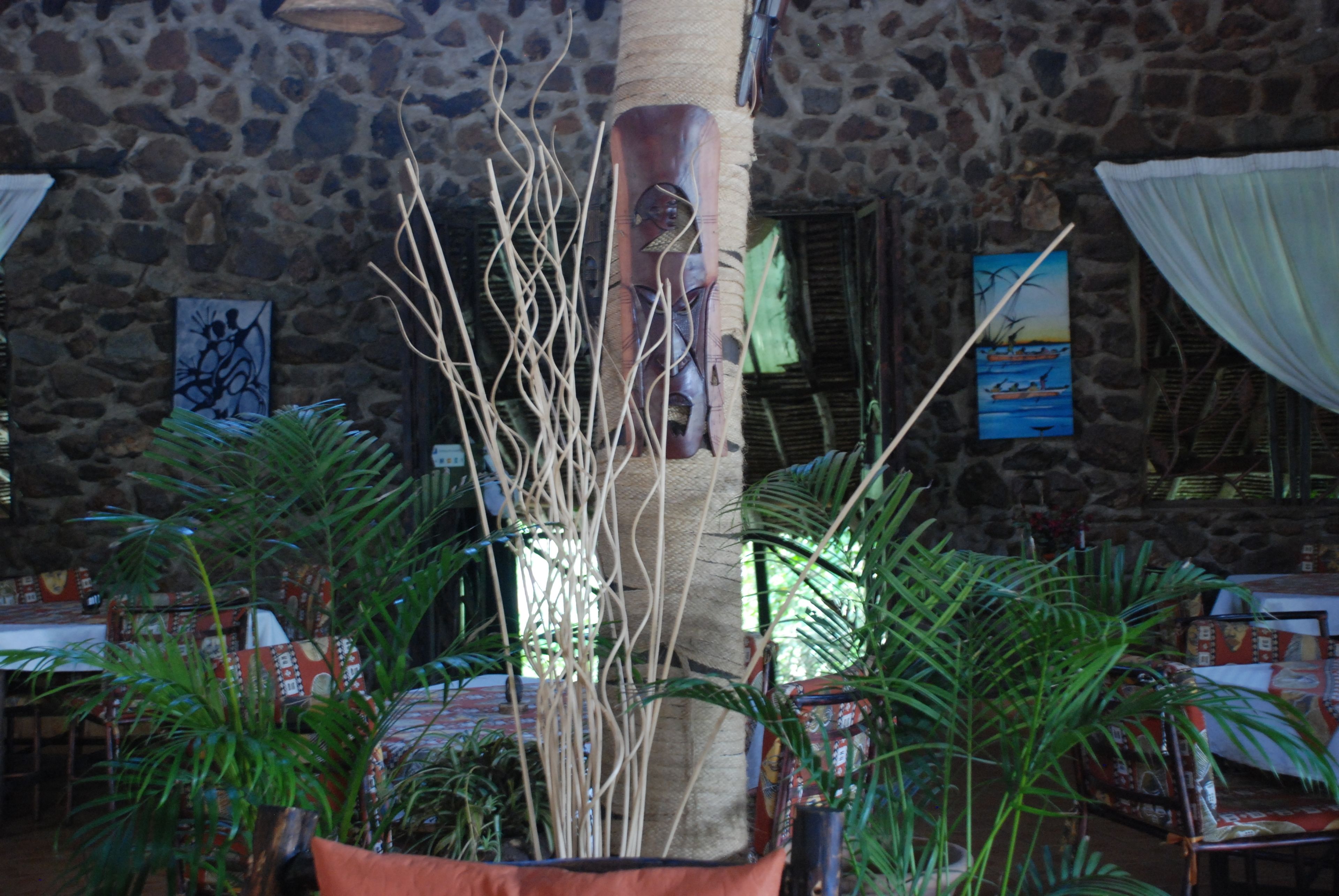A restaurant with stone walls, indoor plants, and tables with red and white tablecloths.