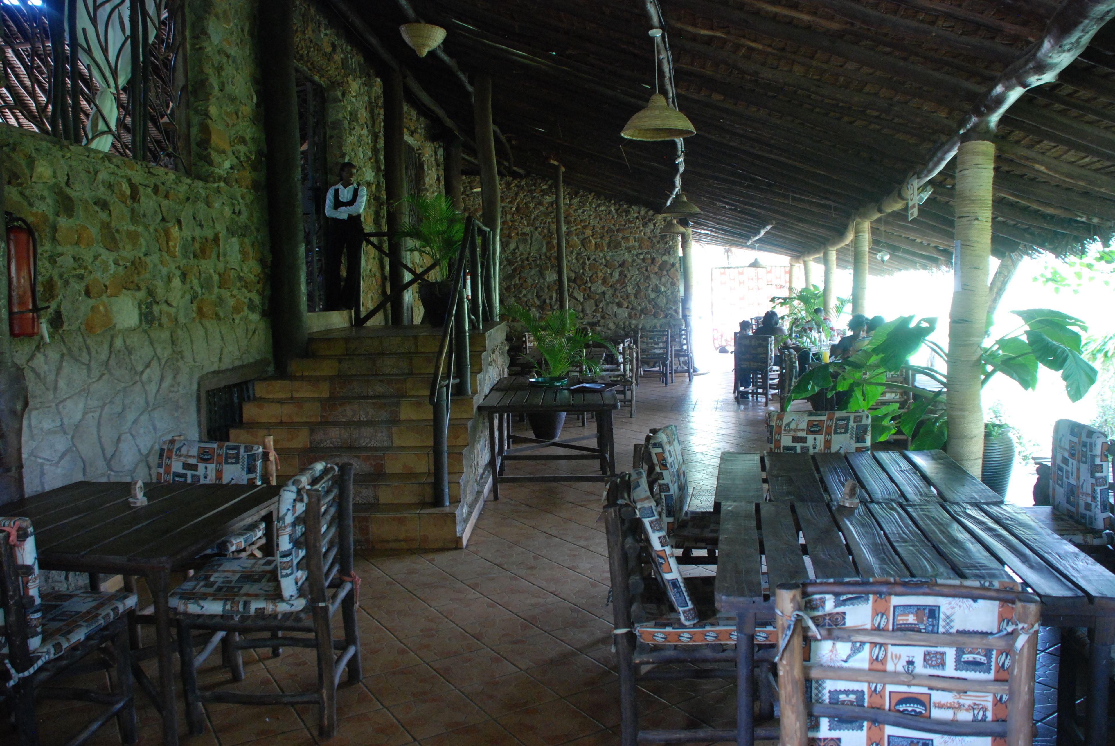 Un espacio de estar al aire libre cubierto, con paredes de piedra y mobiliario de madera.
