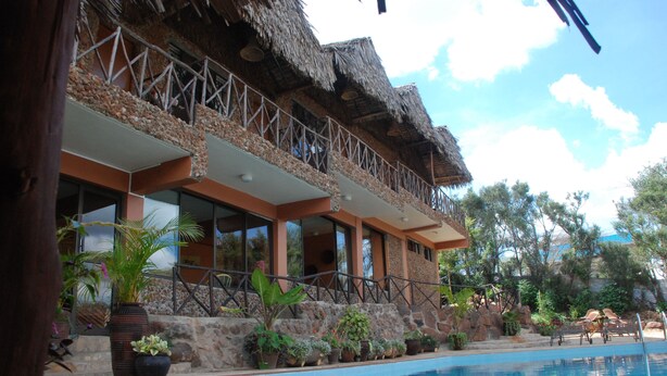 A hotel with a pool, outdoor seating, and a thatched roof balcony. - Osoita Lodge (Ongata Rongai)
