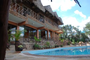 A hotel with a pool, outdoor seating, and a thatched roof balcony. - Osoita Lodge (Ongata Rongai)