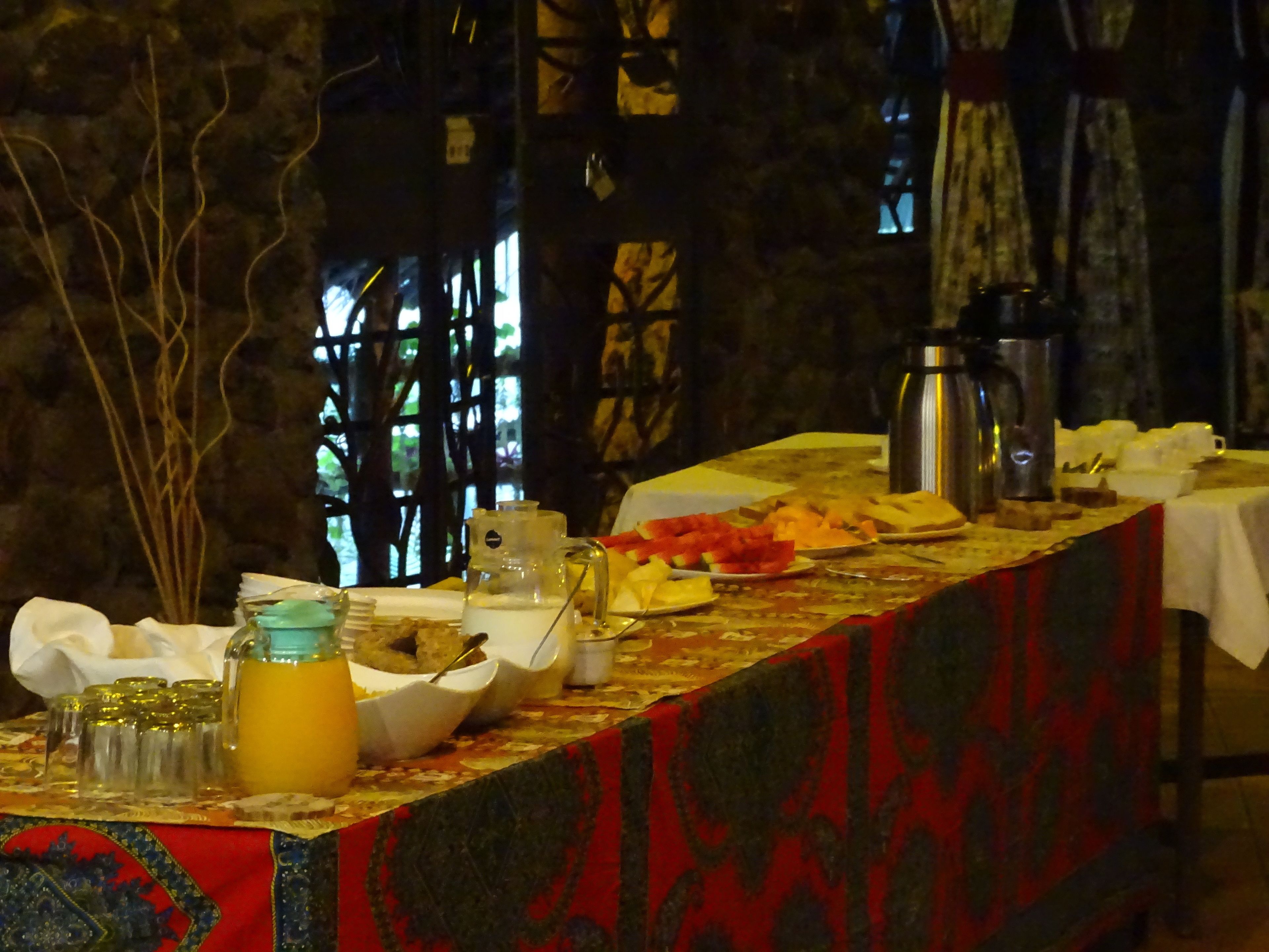 Un bufé de desayuno con diferentes alimentos y una cafetera sobre la mesa.