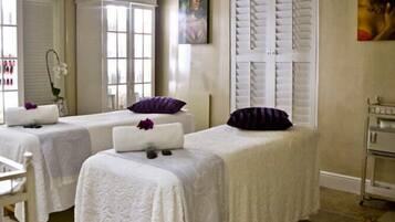 Relax in a serene spa room with two treatment beds, a large window, and a pendant light.