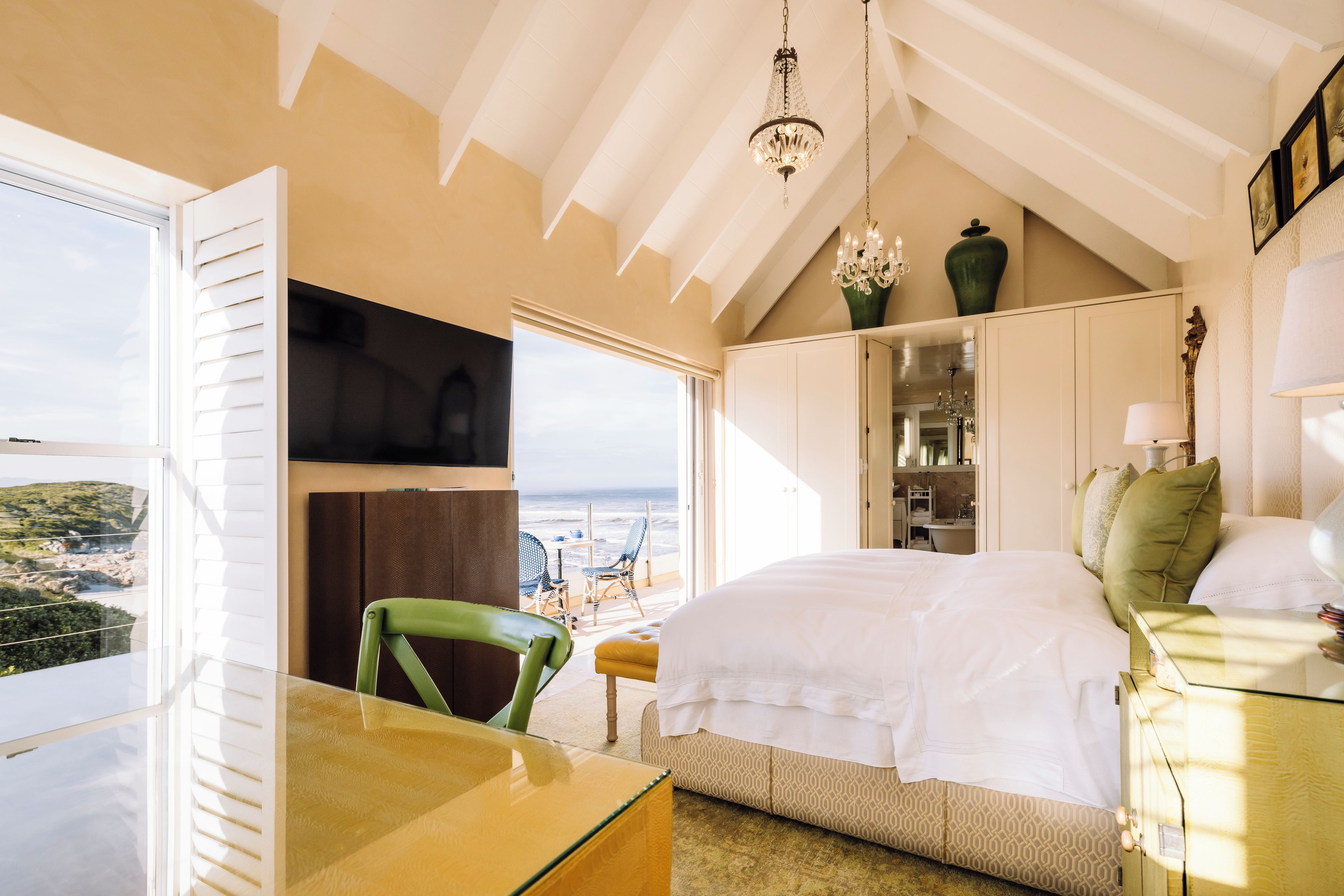 Un dormitorio con cama, escritorio y vista al mar.