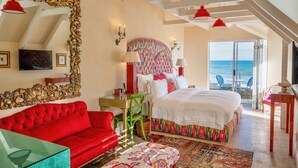 A bedroom with a large bed, a red sofa, a green chair, and a large mirror. - Birkenhead House (Hermanus)