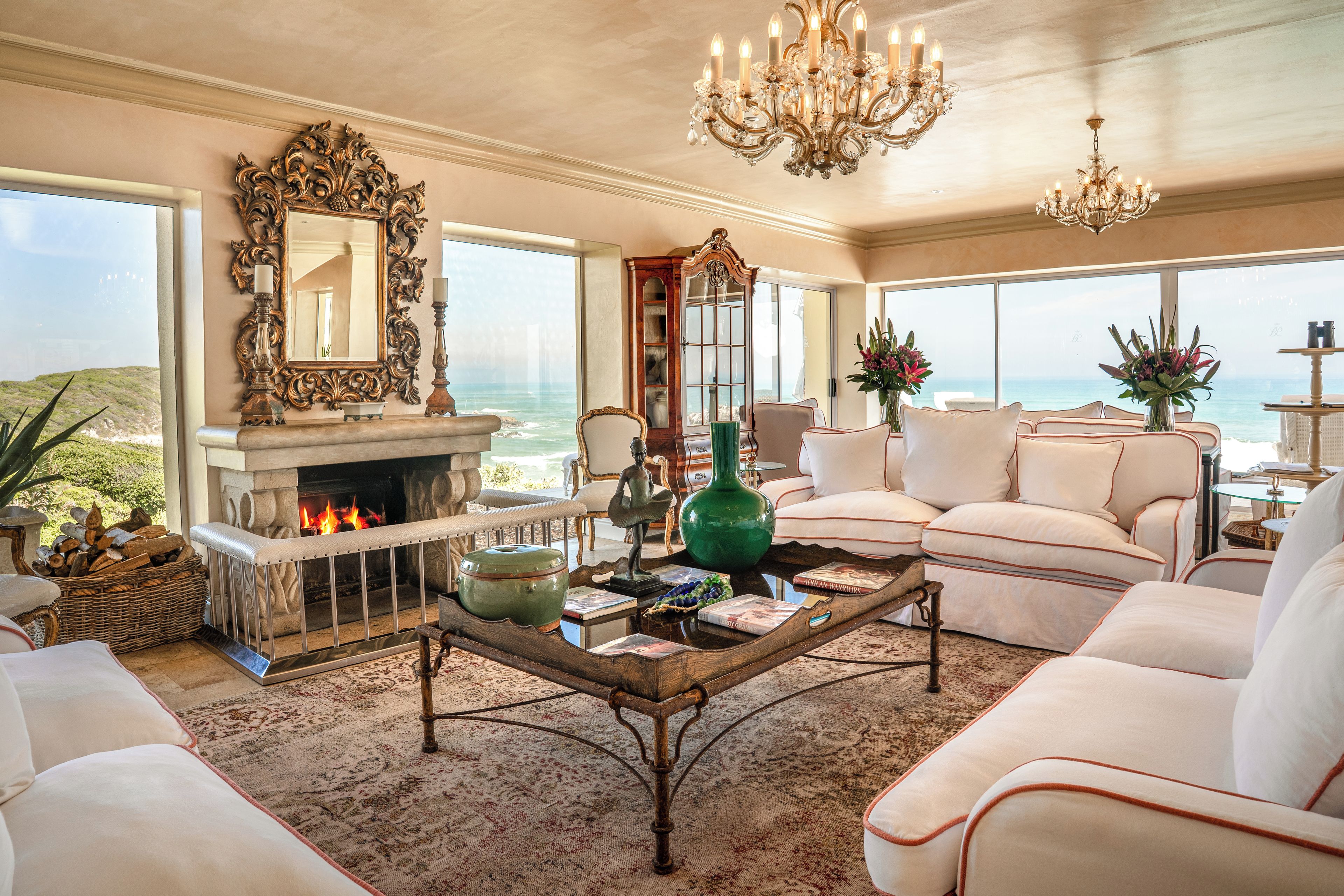 A spacious living room with a fireplace, comfortable seating, and a view of the ocean.