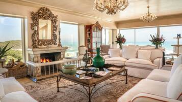 A spacious living room with a fireplace, comfortable seating, and a view of the ocean.