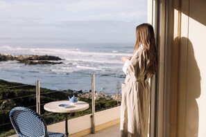 A balcony with a view of the ocean, a table with a teapot, and a chair. - Birkenhead House (Hermanus)