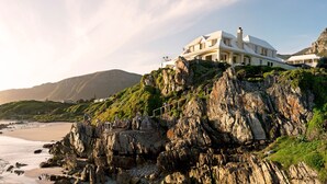 A coastal property with a large house overlooking a rocky beach and ocean. - Birkenhead House (Hermanus)