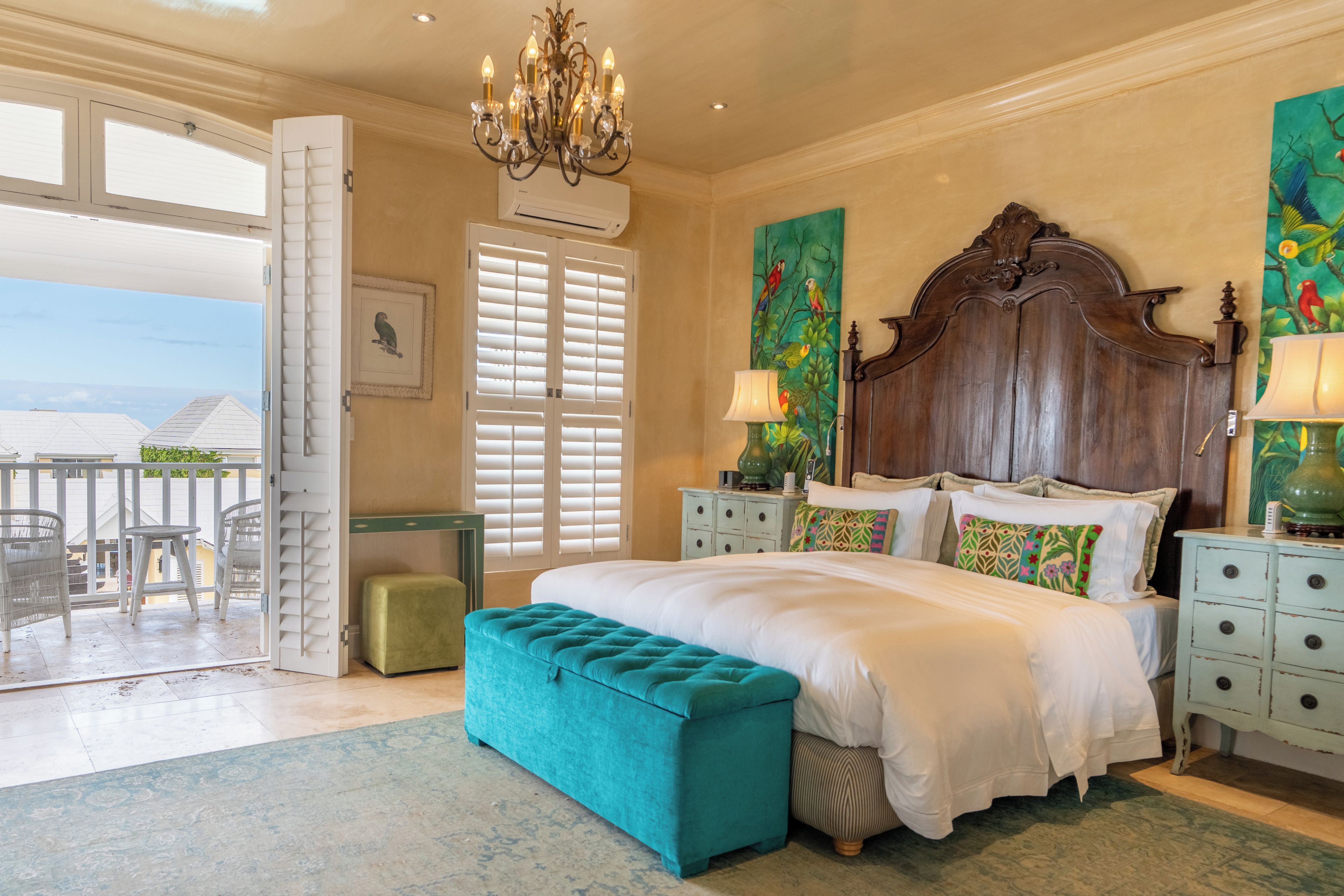 Ein Schlafzimmer mit einem großen Bett, einer Kristallleuchter, Blick ins Freie und einem Balkon.