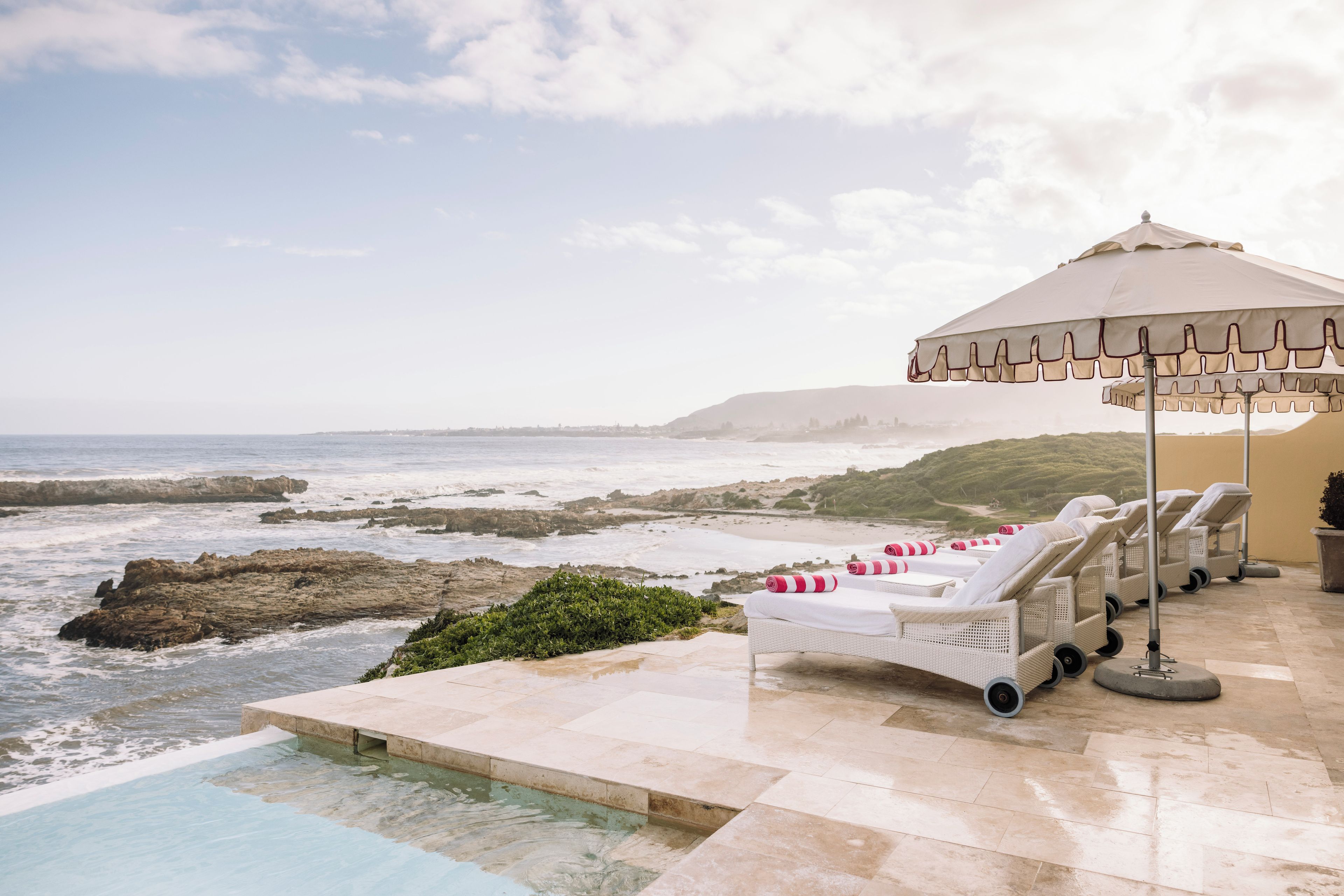 A beachside pool area with lounge chairs and a canopy.