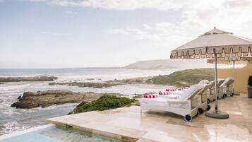 A beachside pool area with lounge chairs and a canopy.