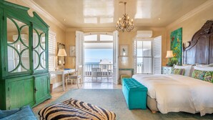 A spacious bedroom with a large bed, a green wardrobe, a balcony with a view, and a chandelier. - Birkenhead House (Hermanus)