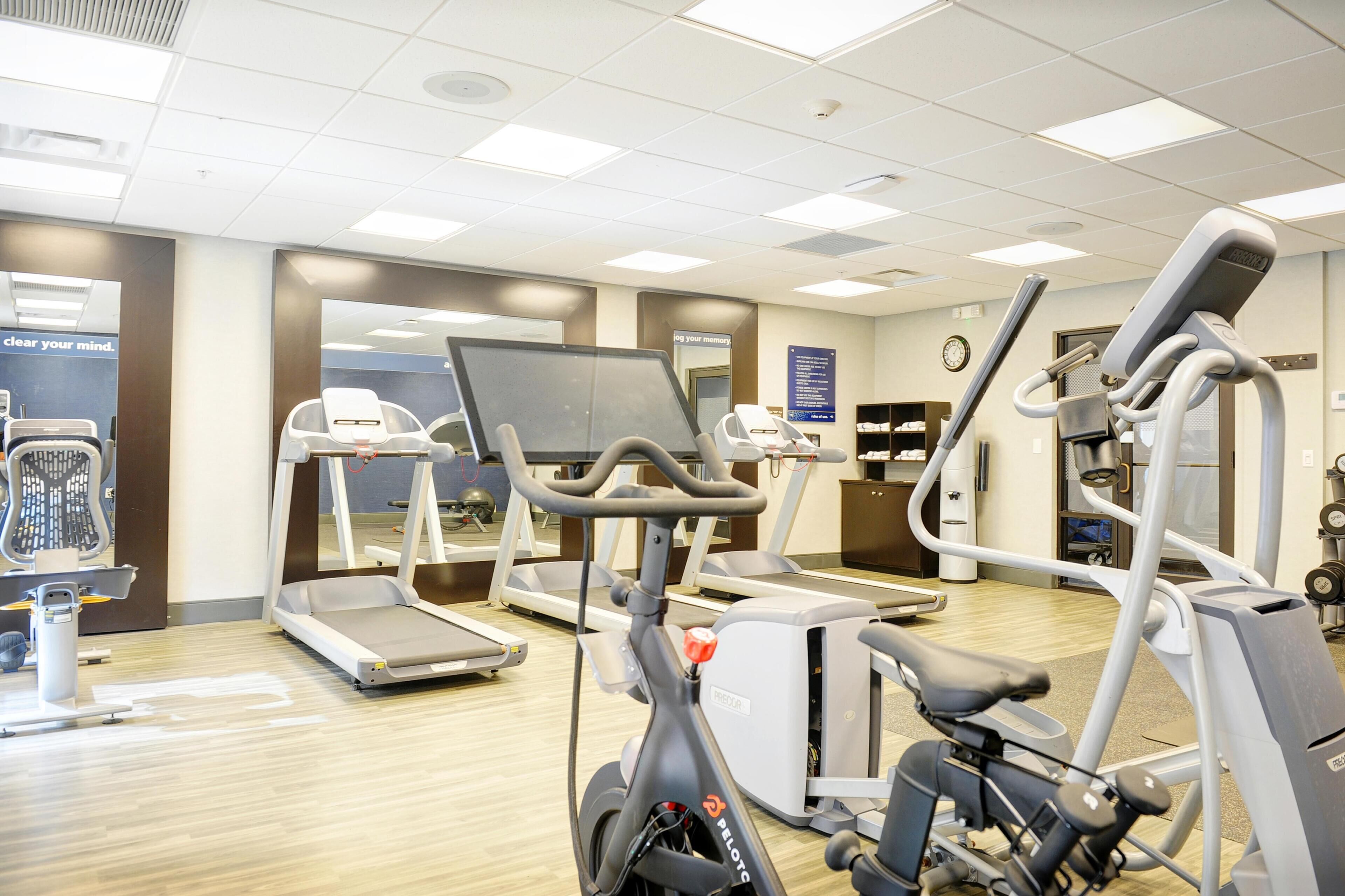 Une salle de sport équipée de tapis de course, d’un vélo elliptique et d’un vélo d’appartement.