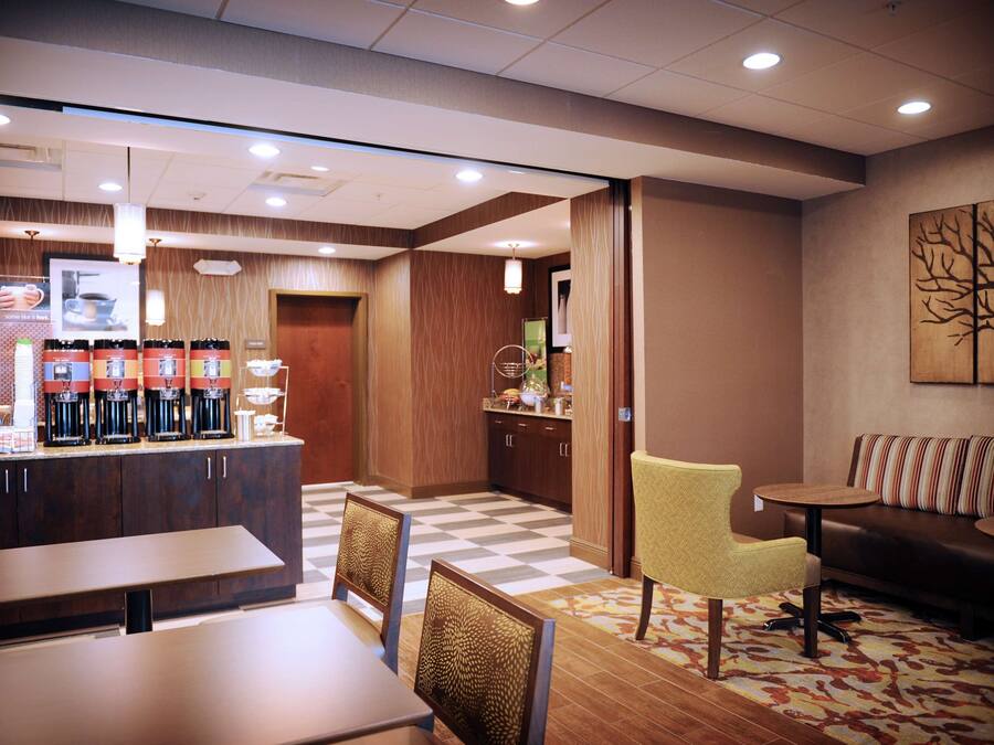Eine Hotelhalle mit Kaffeebar, Sitzgelegenheiten und einer Rezeption.