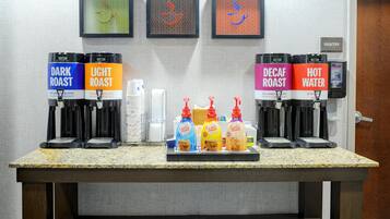 A coffee station with labeled dispensers for dark roast, light roast, decaf roast, and hot water.