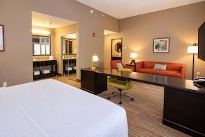 Una habitación de hotel con cama, escritorio, silla y sofá.