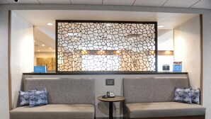 A hotel reception area with a seating area, a reception desk, and a decorative wall.