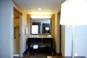 A modern bathroom with a dark vanity, a large mirror, and a bright overhead light.