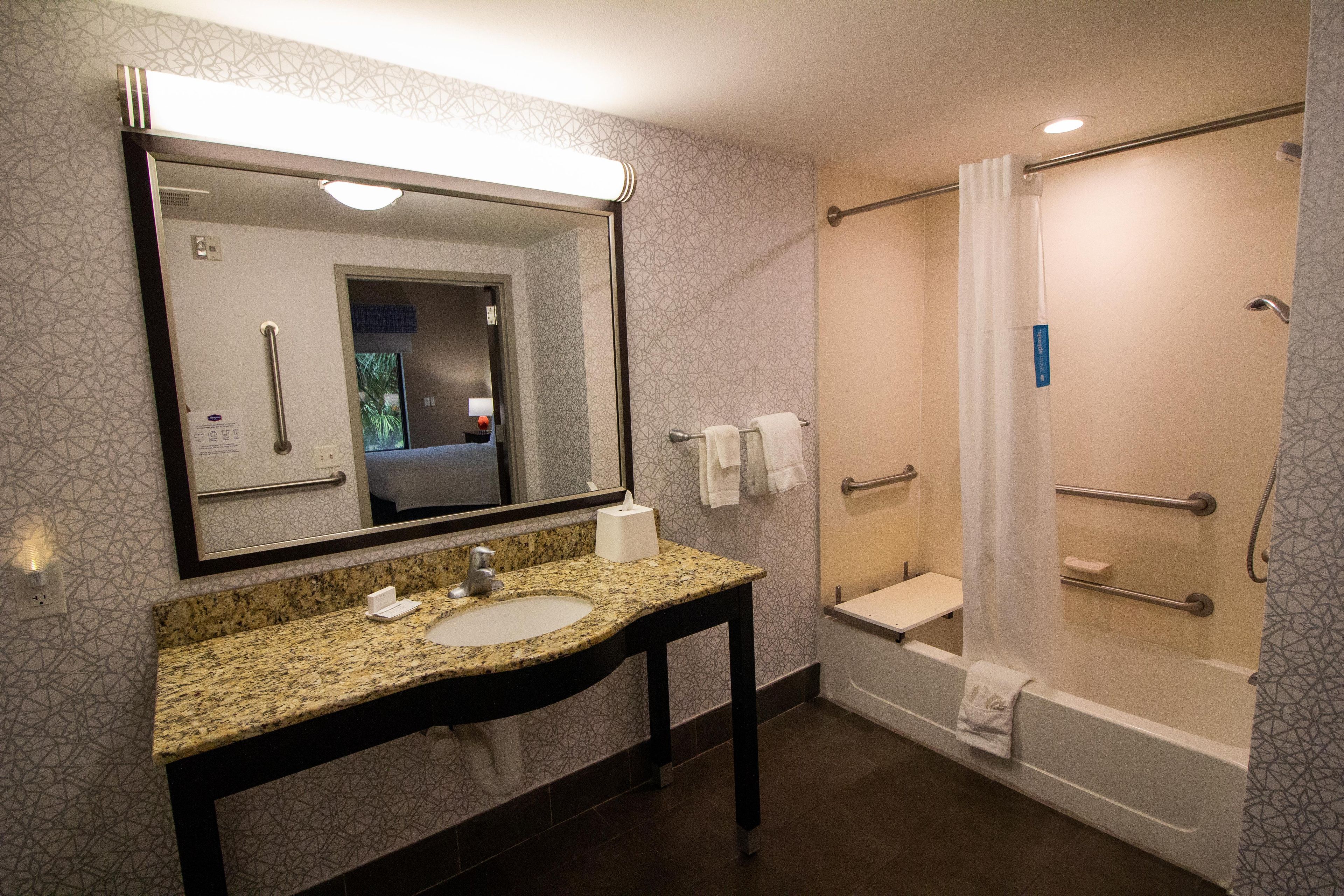 A bathroom with a sink, mirror, and shower.