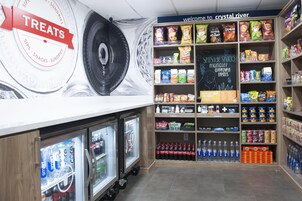 Una sección de aperitivos y bebidas con estantes llenos de papas fritas, bocadillos y bebidas embotelladas.