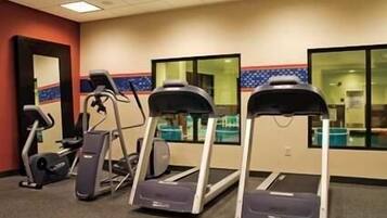 Ein Fitnessraum mit Laufbändern, Ergometer und einer Spiegelwand.