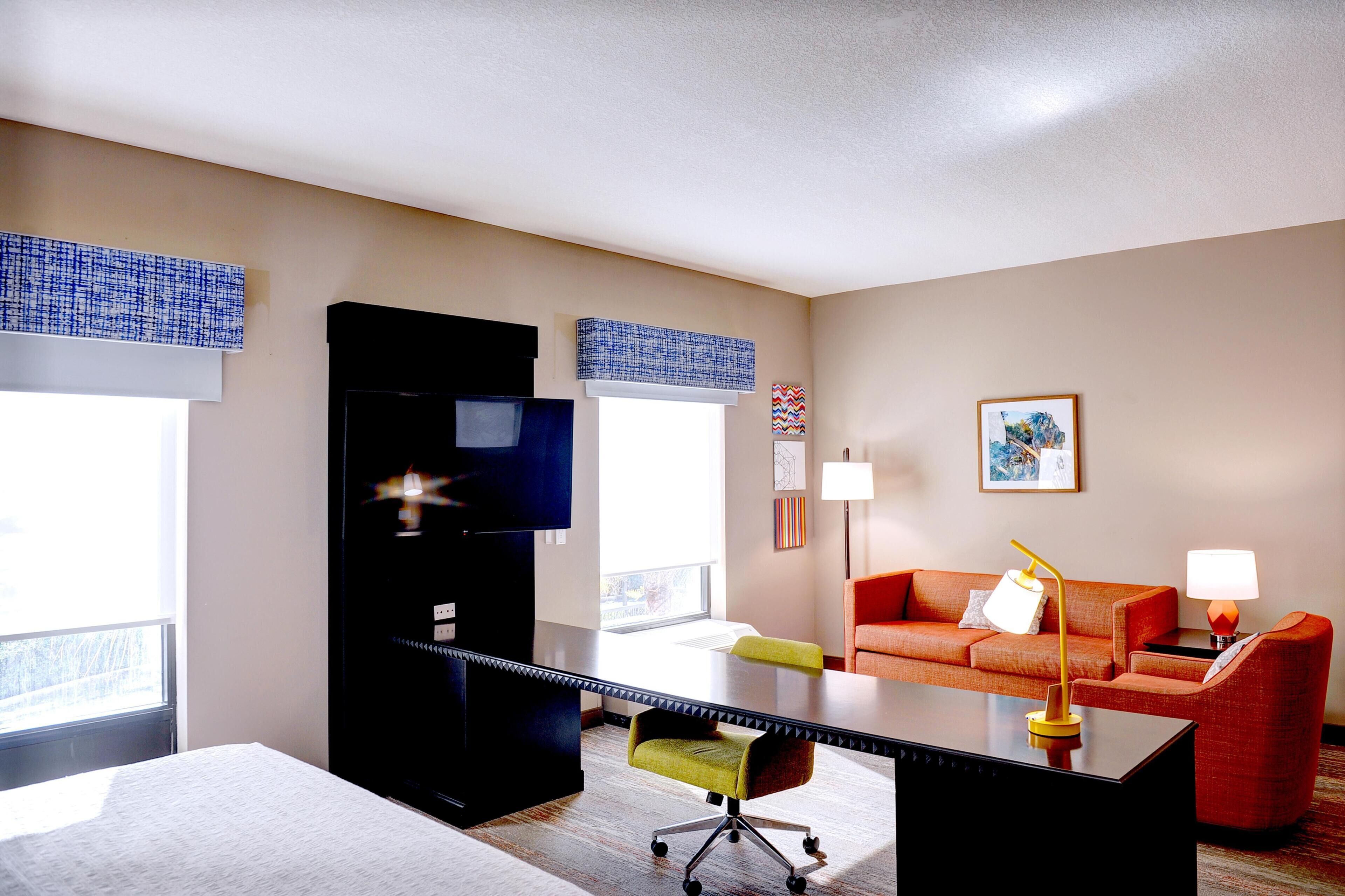 Habitació d'hotel amb un escriptori gran, un sofà, una cadira i una làmpada.