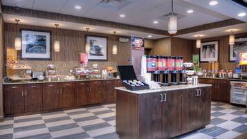 A hotel kitchen with a central island, wooden cabinets, and a checkered floor.