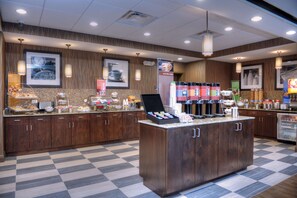 A hotel kitchen with a central island, wooden cabinets, and a checkered floor.