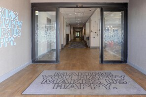 A hotel entrance with a glass door, a hallway leading to the interior, and a doormat with a motivational message. - Hampton Inn Crystal River, FL (Crystal River)