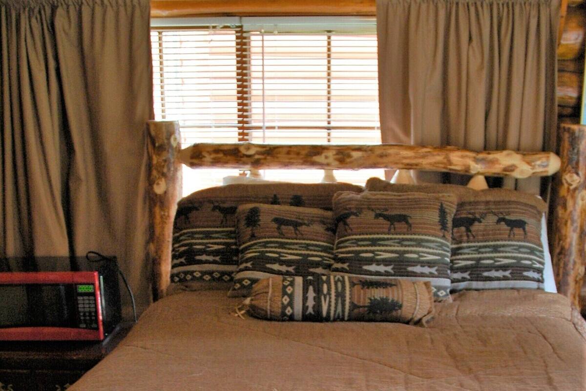 Un lit avec une tête de lit en bois, des coussins à motifs et une couverture marron.