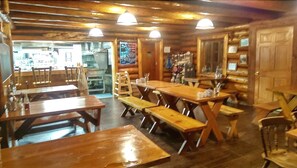 Un intérieur rustique en bois, avec des tables et des bancs, un coin cuisine et un bar.