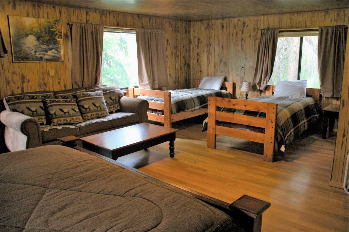 Une cabine comprenant deux lits en bois, un canapé, une table et une fenêtre avec des rideaux.