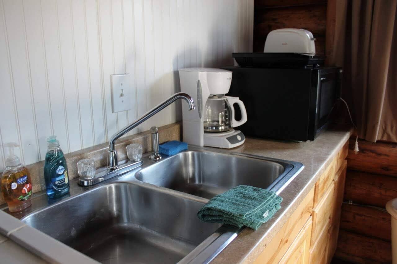 A kitchen with a double sink, a coffee maker, and a microwave.