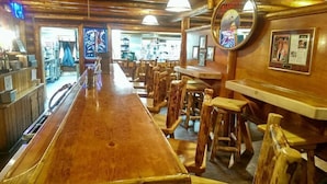 Un área de bar con taburetes de madera y una barra alargada.