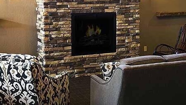 A stone fireplace with a framed picture above it, flanked by wall sconces.
