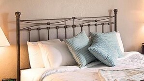 A bed with a metal frame, white bedding, and two light blue pillows.